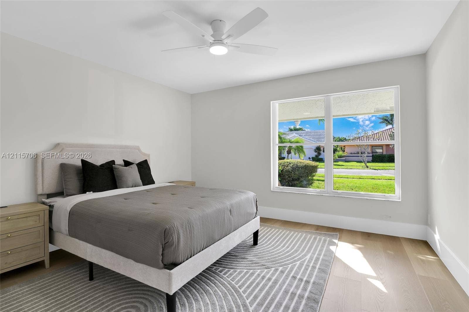 5184 Deerhurst Crescent Circle, Boca Raton, FL 33486 Neutral wall palette featuring wood-finish flooring, a large picture window, and a central ceiling fan with integrated lighting