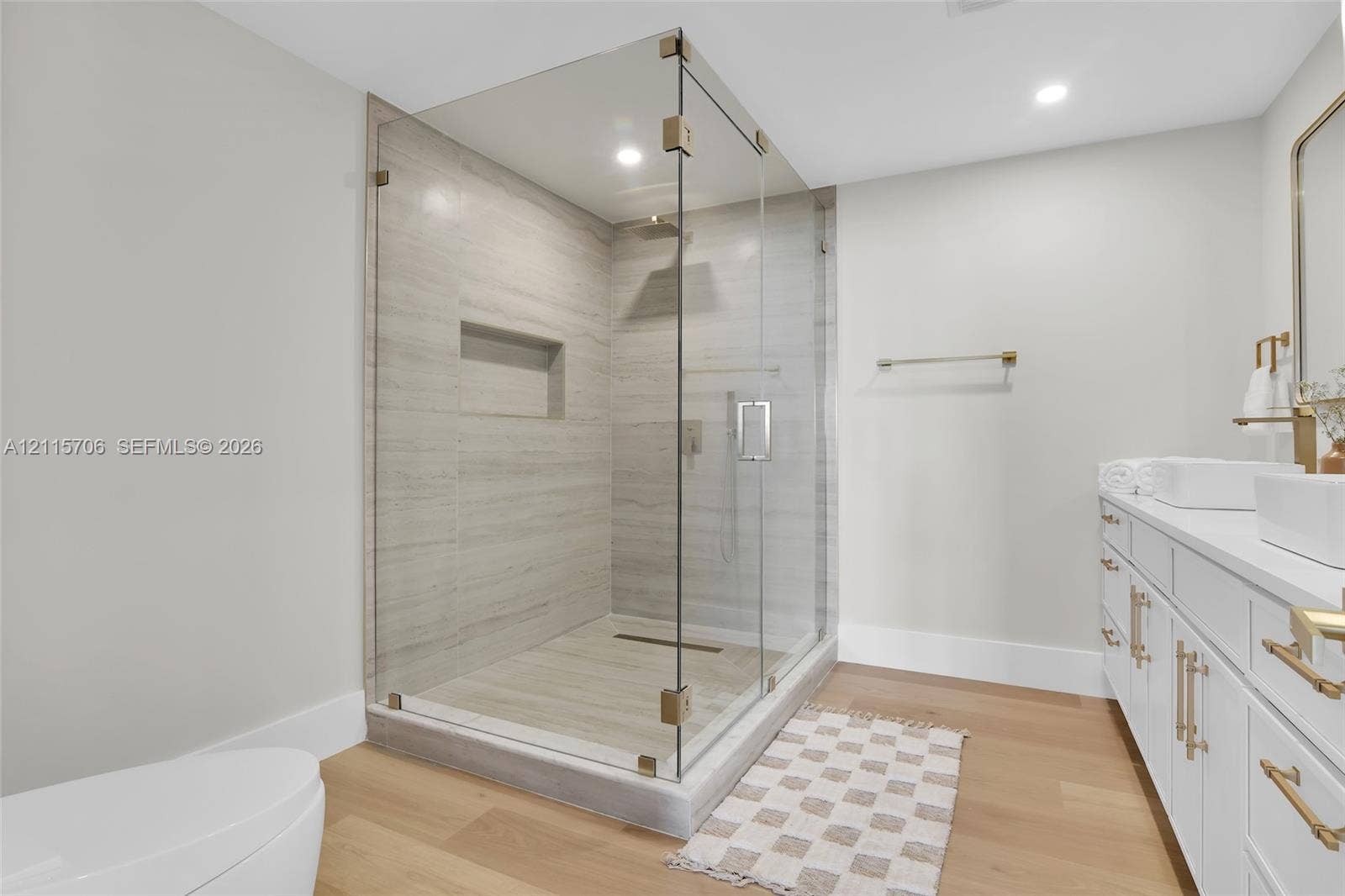 5184 Deerhurst Crescent Circle, Boca Raton, FL 33486 Walk-in shower featuring a frameless glass enclosure, floor-to-ceiling stone-style wall tile, and an integrated wall niche