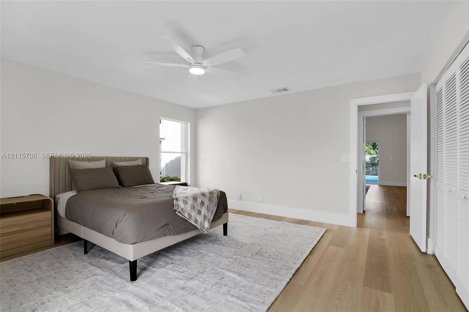5184 Deerhurst Crescent Circle, Boca Raton, FL 33486 Neutral-toned room featuring wood-finish flooring, a white ceiling fan with integrated lighting, and louvered closet doors