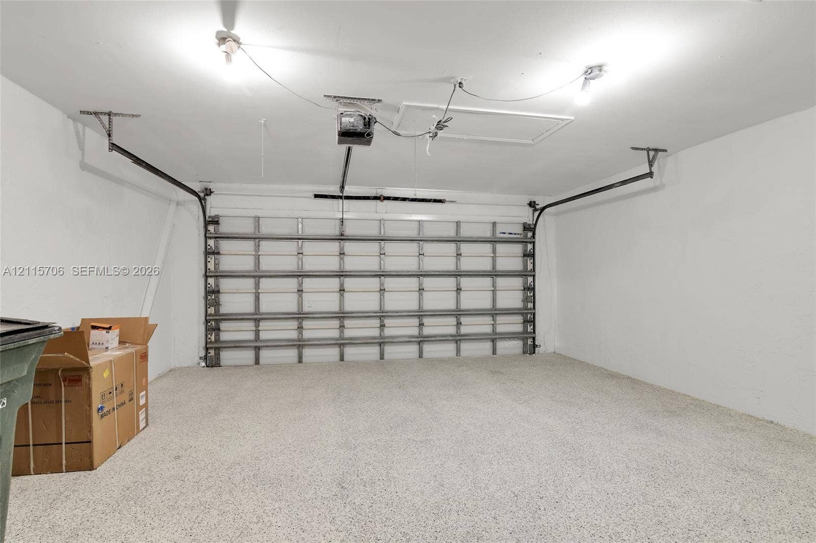 5184 Deerhurst Crescent Circle, Boca Raton, FL 33486 Two-car garage featuring a speckled epoxy-coated floor, high-ceiling configuration, automated door opener, and access panel