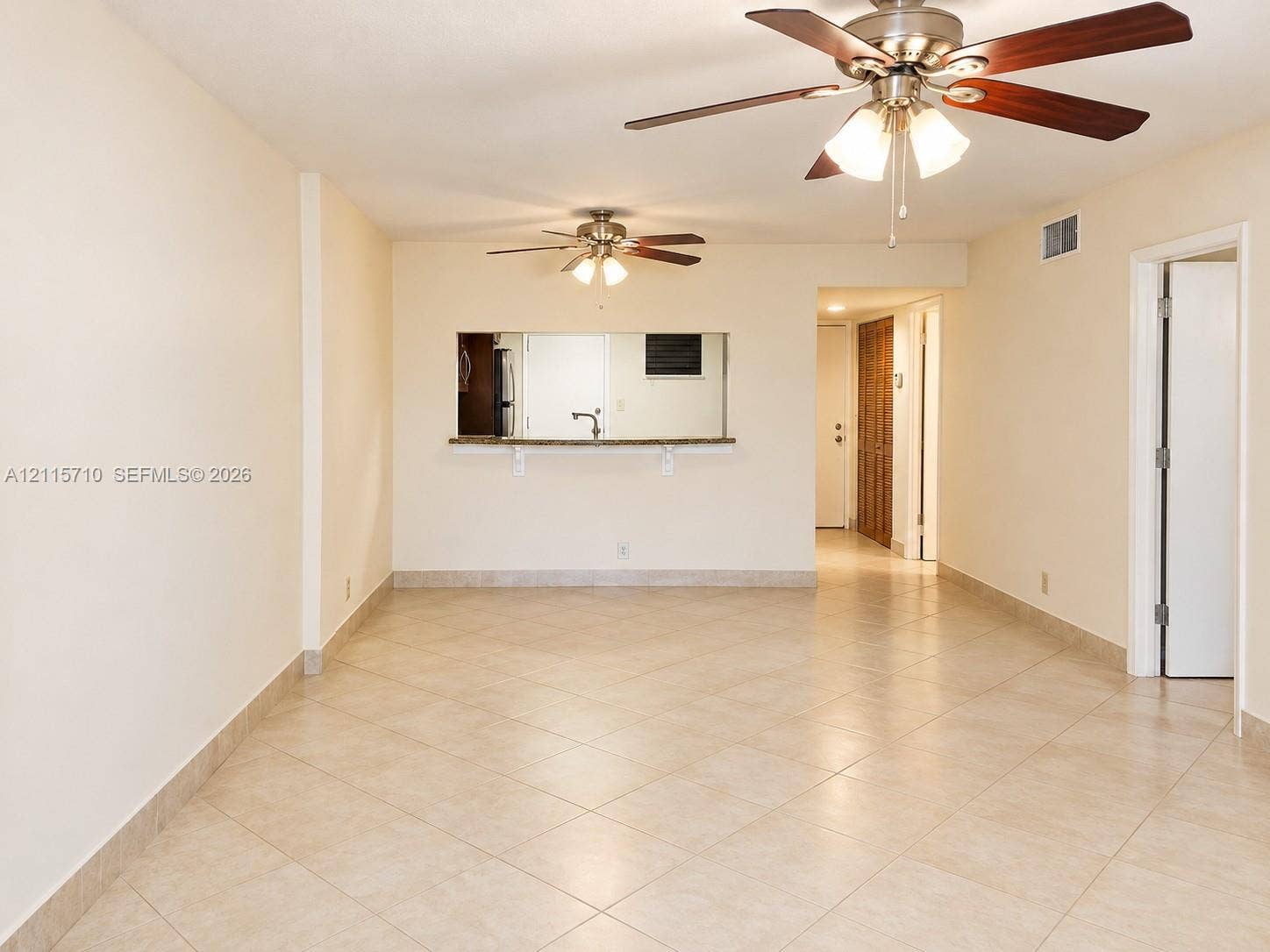 406 NW 68th Avenue, #115, Plantation, Plantation, FL 33317 Neutral ceramic tile flooring, dual ceiling fans with integrated lighting fixtures, and a stone-surface pass-through window with an attached service counter