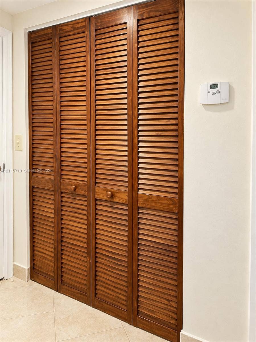 406 NW 68th Avenue, #115, Plantation, Plantation, FL 33317 Four-panel closet featuring stained wood louvered doors with circular wood knobs and neutral tile flooring