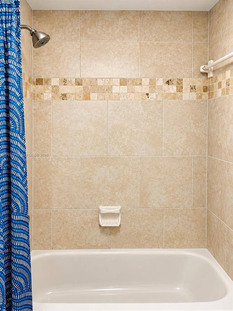 406 NW 68th Avenue, #115, Plantation, Plantation, FL 33317 Full-height tile shower surround featuring neutral-toned stone-finish wall tile, an integrated mosaic accent band, a built-in soap dish, and a wall-mounted shower head