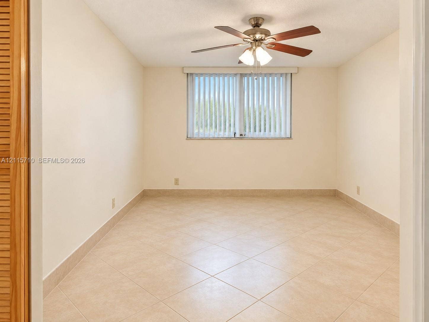 406 NW 68th Avenue, #115, Plantation, Plantation, FL 33317 Interior room featuring large-format tile flooring, multi-blade ceiling fan with integrated light fixture, vertical window blinds, and built-in closet with louvered doors