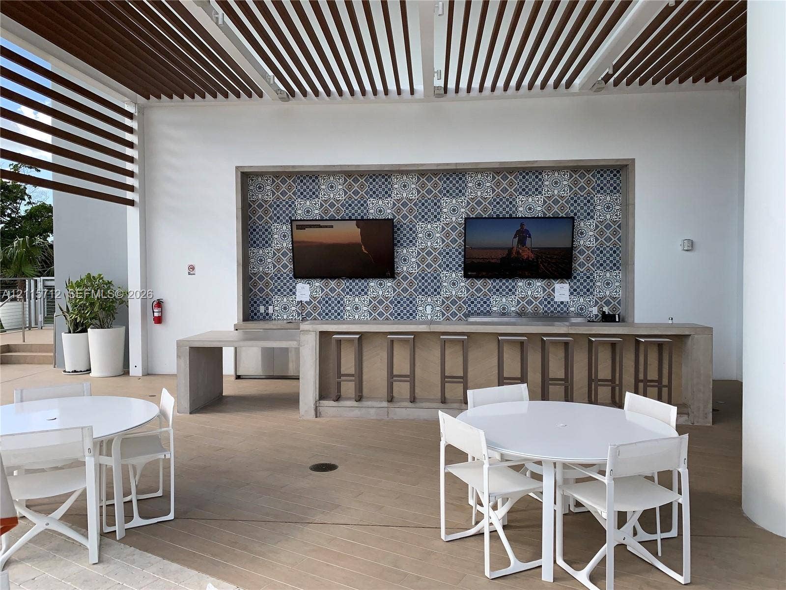16385 Biscayne Boulevard, #1906, North Miami Beach, North Miami Beach, FL 33160 Outdoor covered patio featuring a slatted pergola ceiling, concrete bar with patterned tile backsplash, and wood-finish flooring