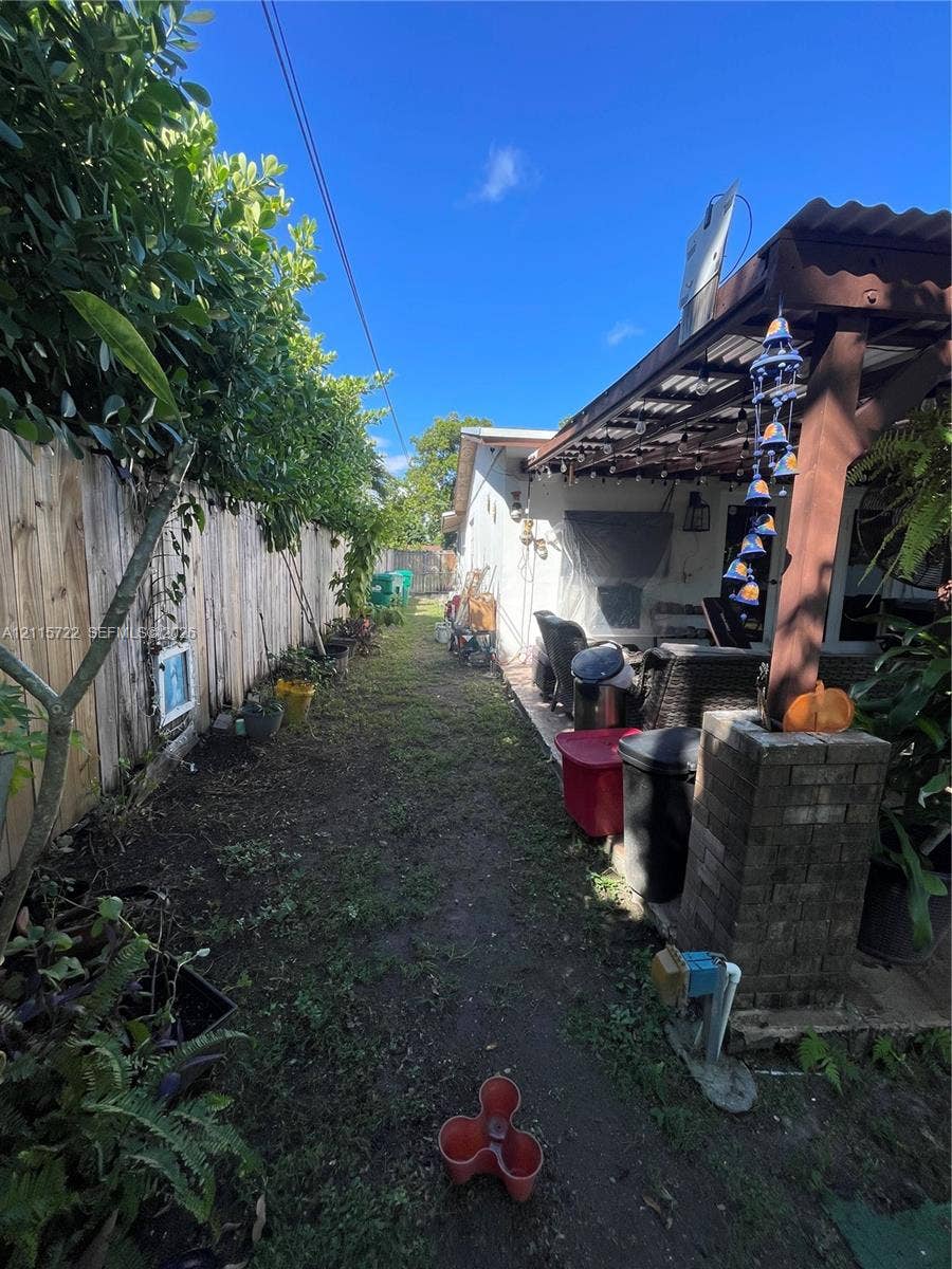 9852 SW 196th Street, Cutler Bay, FL 33157 Side yard featuring a covered patio, brick masonry pillar, and wood-panel privacy fencing
