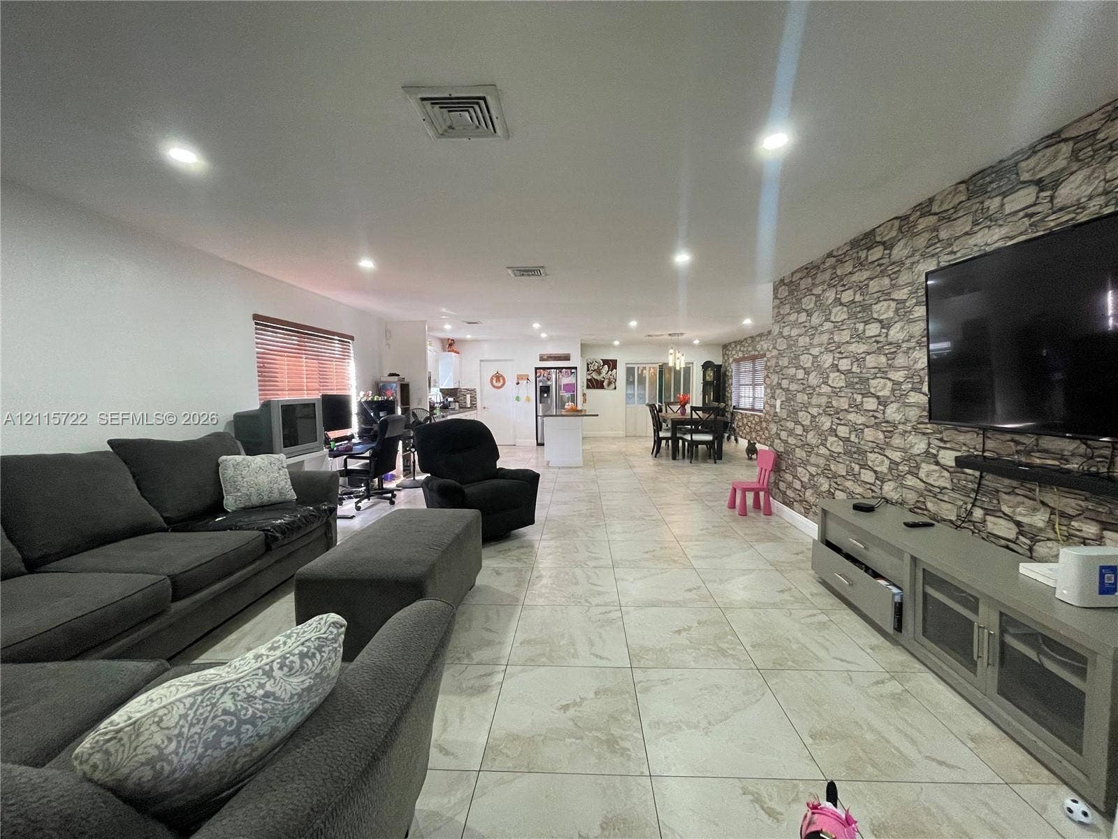 9852 SW 196th Street, Cutler Bay, FL 33157 Open-concept interior featuring large-format ceramic tile flooring, stone-veneer accent wall, and recessed lighting