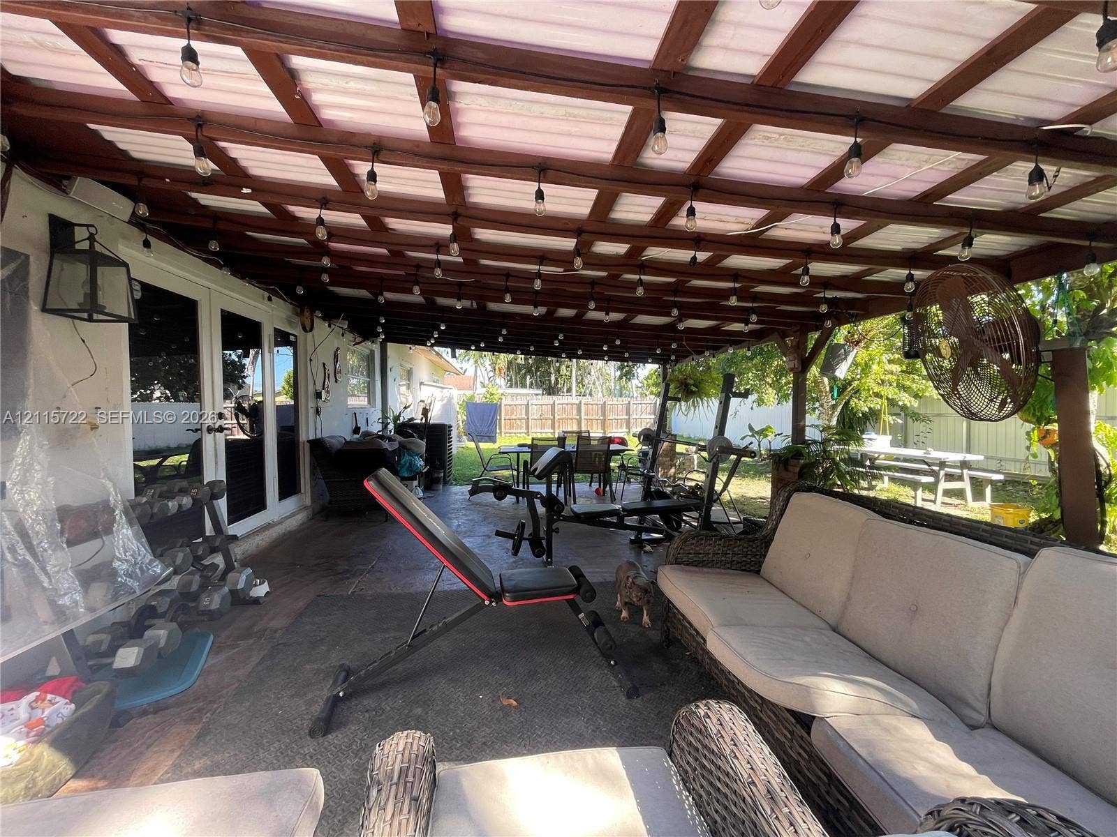 9852 SW 196th Street, Cutler Bay, FL 33157 Covered outdoor patio featuring a wood-beam pergola structure, tiled flooring, mounted string lighting, and an attached wall-mounted fan