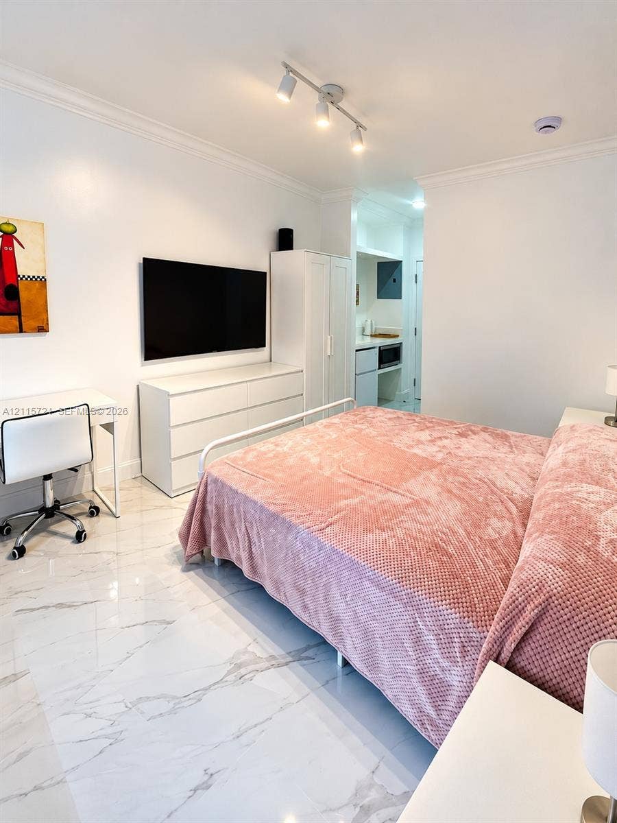 Large-format polished stone flooring, three-bulb adjustable ceiling track lighting, and crown molding