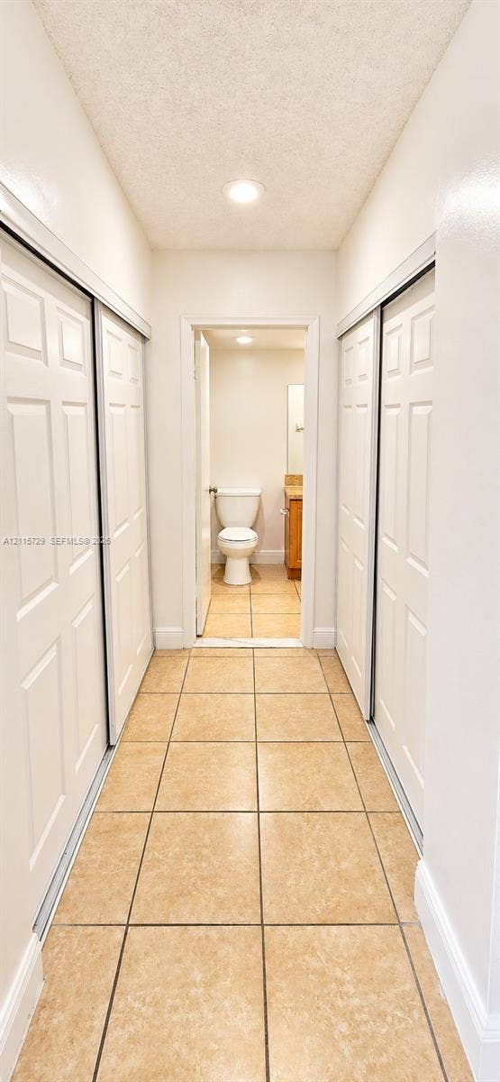 11110 SW 196th Street, #212, Cutler Bay, Cutler Bay, FL 33157 Hallway featuring ceramic tile flooring, recessed ceiling lighting, and dual sets of white paneled sliding closet doors