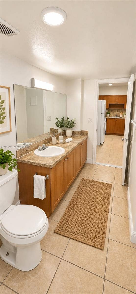 11110 SW 196th Street, #212, Cutler Bay, Cutler Bay, FL 33157 Bathroom featuring a wood-toned vanity cabinet, stone-finish countertop with an integrated basin, wall-to-wall mirror, and ceramic tile flooring