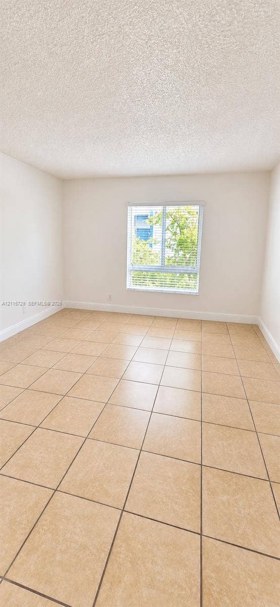 11110 SW 196th Street, #212, Cutler Bay, Cutler Bay, FL 33157 Interior space featuring neutral-toned tile flooring, light-colored walls, textured ceiling, and a single window with horizontal blinds