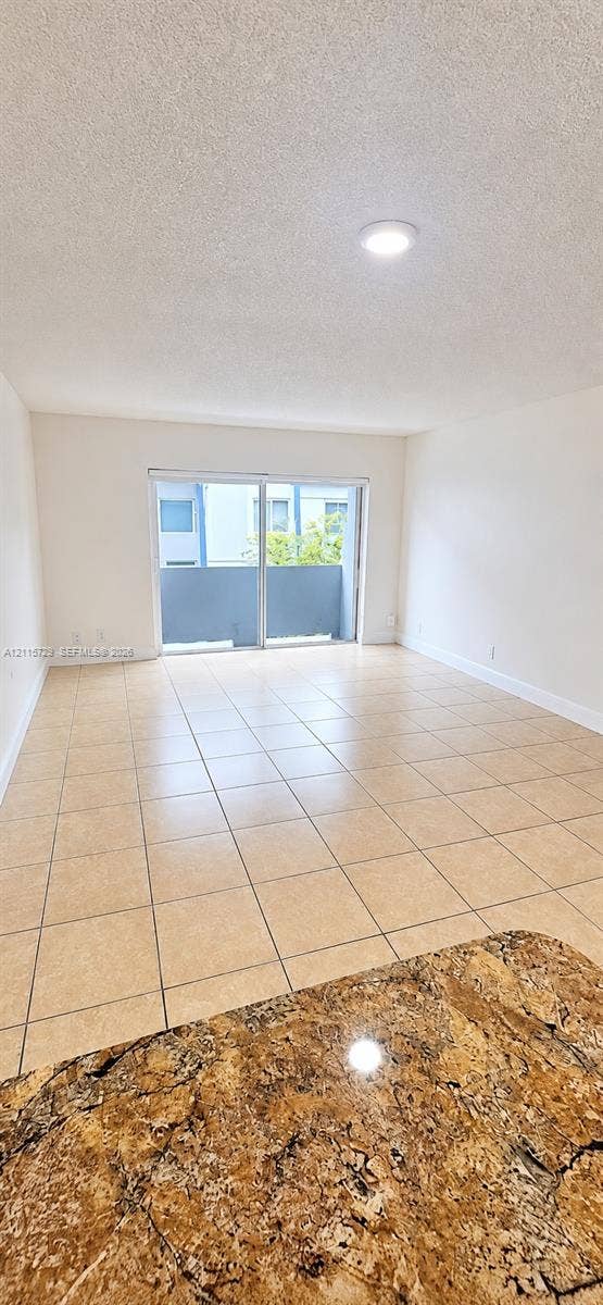 11110 SW 196th Street, #212, Cutler Bay, Cutler Bay, FL 33157 Open-concept room featuring neutral tile flooring, recessed ceiling lighting, and sliding glass doors leading to an exterior balcony