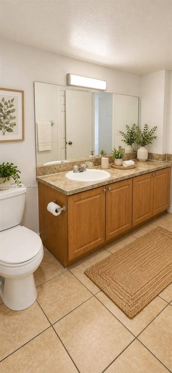 11110 SW 196th Street, #212, Cutler Bay, Cutler Bay, FL 33157 Bathroom vanity featuring wood-finish cabinetry, a stone-composite countertop with an integrated basin, large wall-mounted mirror, and ceramic tile flooring