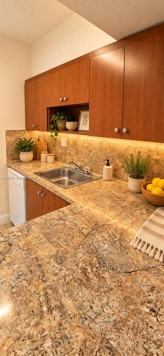 11110 SW 196th Street, #212, Cutler Bay, Cutler Bay, FL 33157 Kitchen featuring wood cabinetry, stone-finish countertops, an integrated under-cabinet lighting system, a stainless steel sink with a dual-handle faucet, and an open display niche