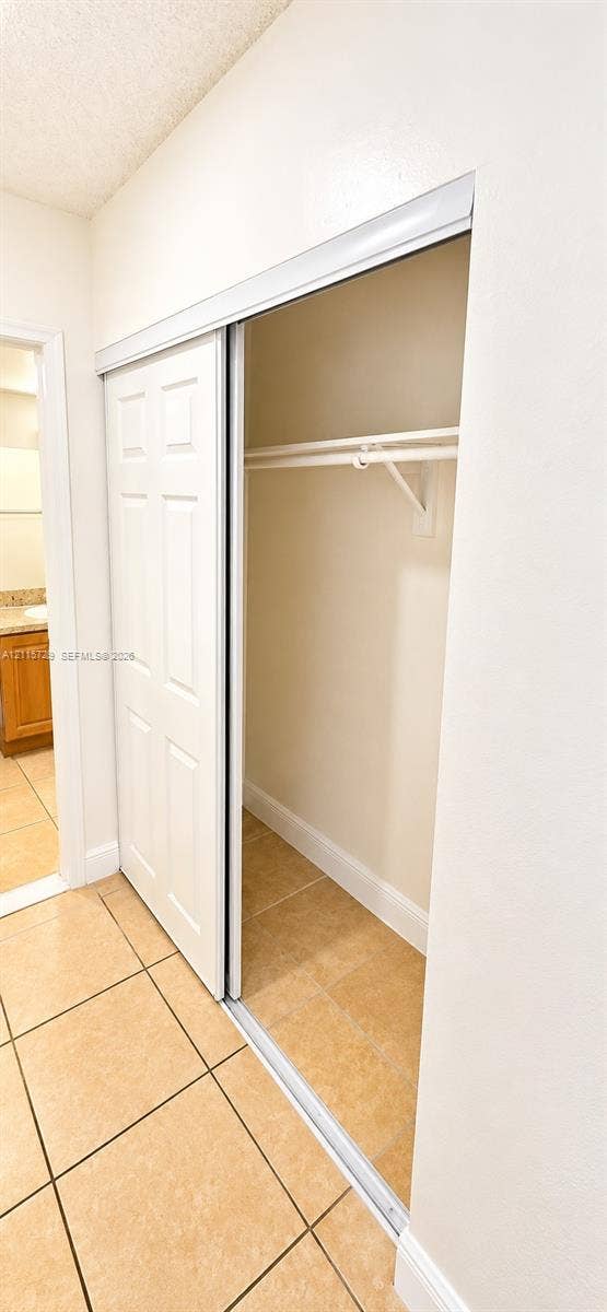 11110 SW 196th Street, #212, Cutler Bay, Cutler Bay, FL 33157 Closet featuring white six-panel sliding doors, a white overhead hanging rod, and tile flooring