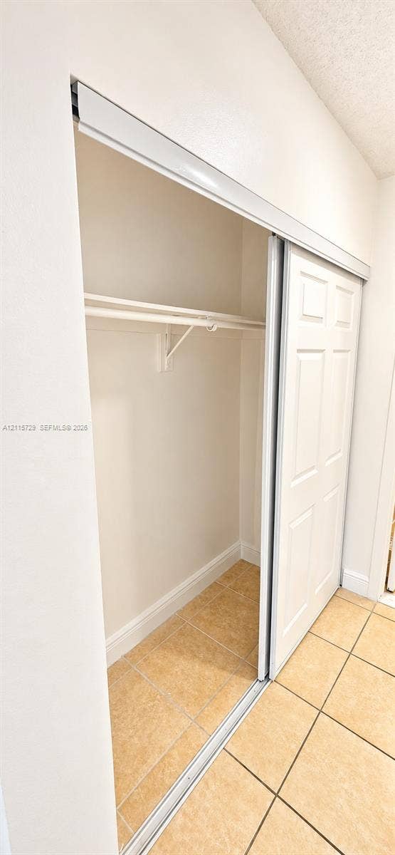 11110 SW 196th Street, #212, Cutler Bay, Cutler Bay, FL 33157 Closet featuring sliding six-panel doors, a built-in hanging rod, a high-mounted shelf, and ceramic tile flooring