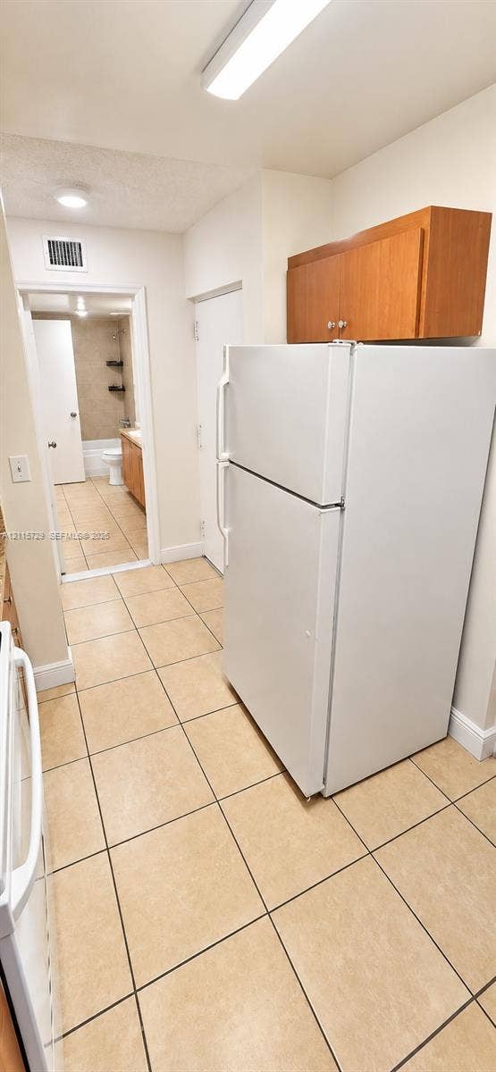 11110 SW 196th Street, #212, Cutler Bay, Cutler Bay, FL 33157 Ceramic tile flooring, white top-mount refrigerator, wood-finish upper cabinetry, and flush-mount ceiling lighting