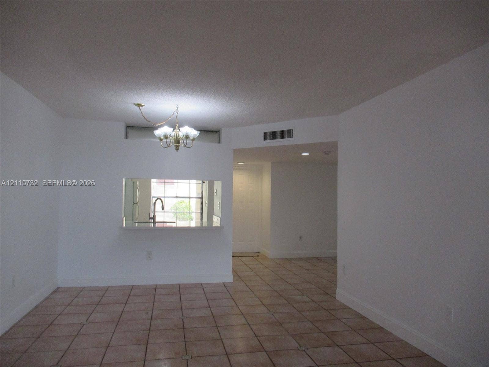 Ceramic tile flooring, multi-light hanging chandelier, and pass-through window with solid-surface counter