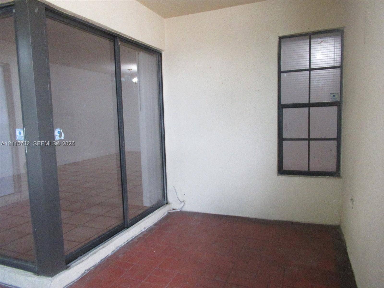 Enclosed patio featuring tile flooring, sliding glass doors with dark metal frames, and a multi-pane window