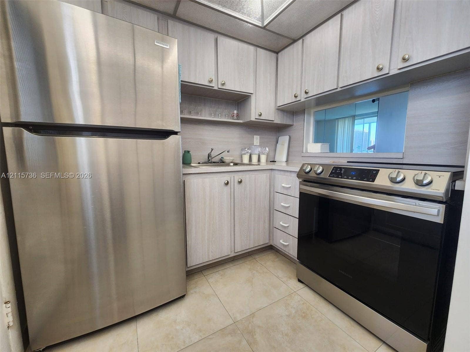 2861 Leonard Drive, #F605, Aventura, FL 33160 Kitchen featuring stainless steel refrigerator, slide-in electric range, light-toned cabinetry, light-toned solid surface countertops, and tile flooring