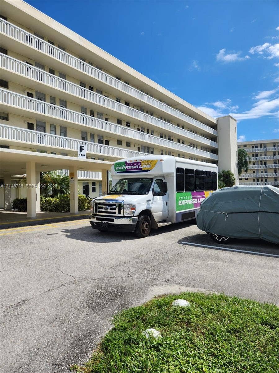 2861 Leonard Drive, #F605, Aventura, FL 33160 Multi-story building exterior featuring a covered entryway with structural columns and tiered balconies with white railings