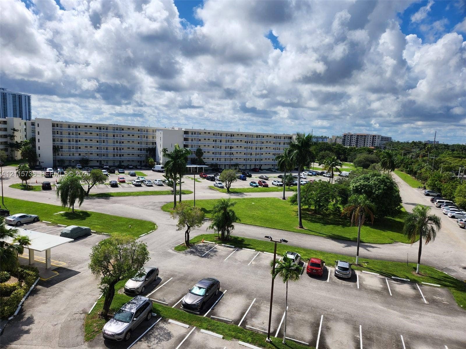 2861 Leonard Drive, #F605, Aventura, FL 33160 Multi-story residential complex featuring paved surface parking, mature palm trees, and landscaped green spaces