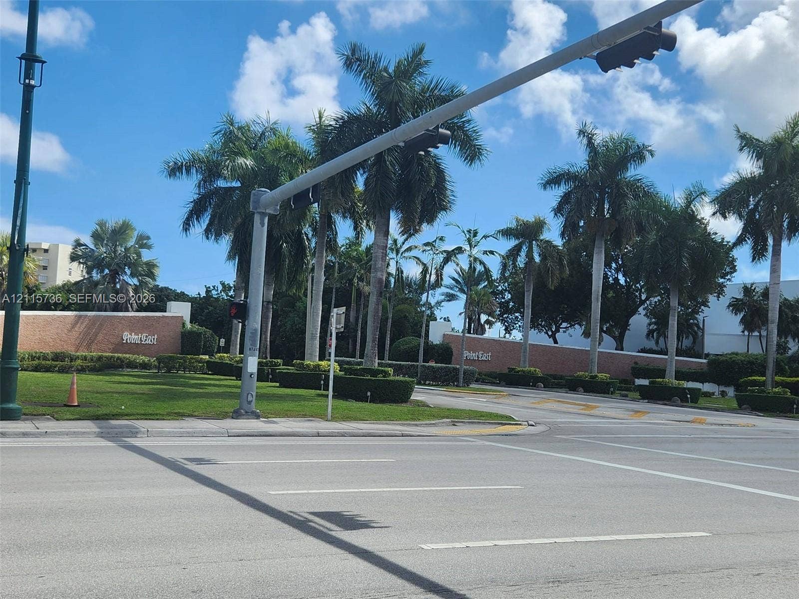 2861 Leonard Drive, #F605, Aventura, FL 33160 Property entrance featuring brick perimeter walls, manicured landscaping, and mature palm trees