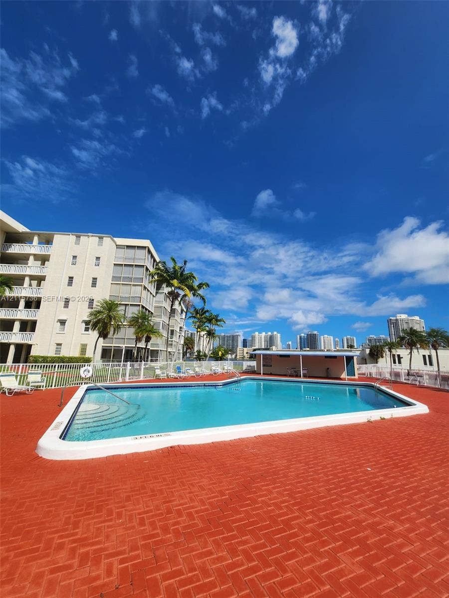 2861 Leonard Drive, #F605, Aventura, FL 33160 Outdoor swimming pool featuring a herringbone-patterned brick deck, tiered entry steps, and a covered pavilion