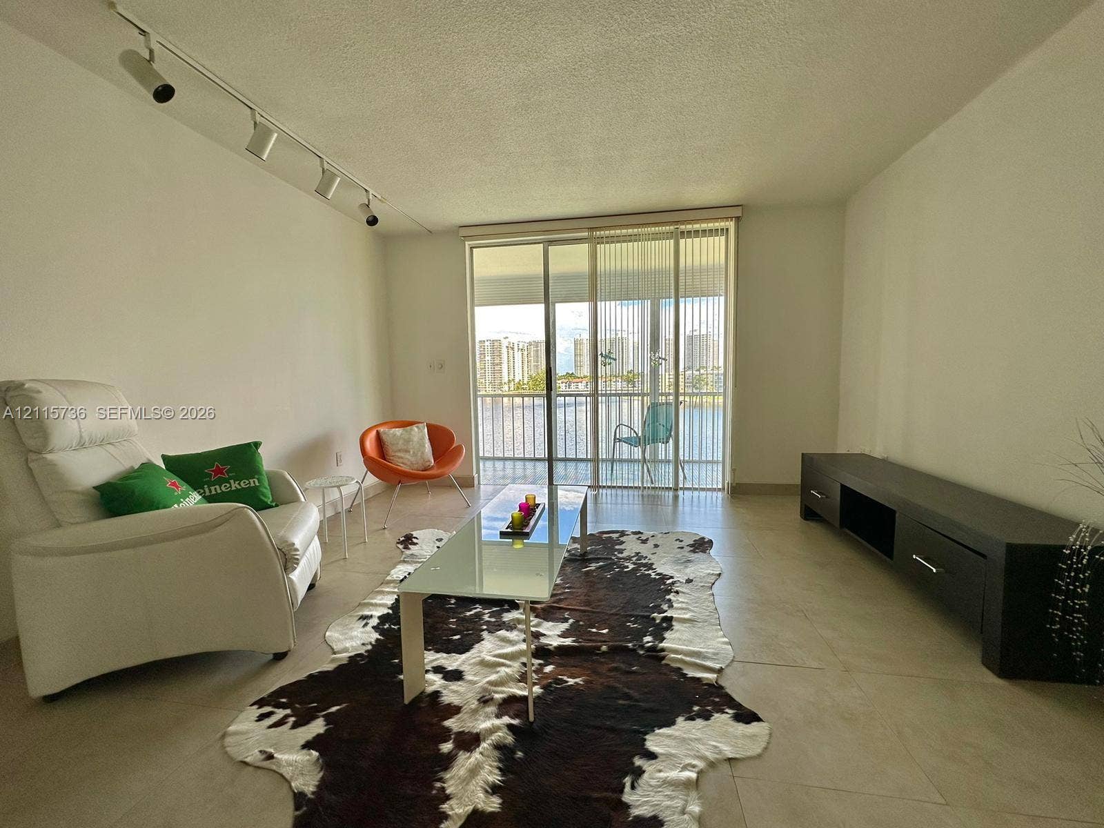 2861 Leonard Drive, #F605, Aventura, FL 33160 Large-format tile flooring, ceiling-mounted track lighting, and full-height sliding glass doors opening to a private balcony