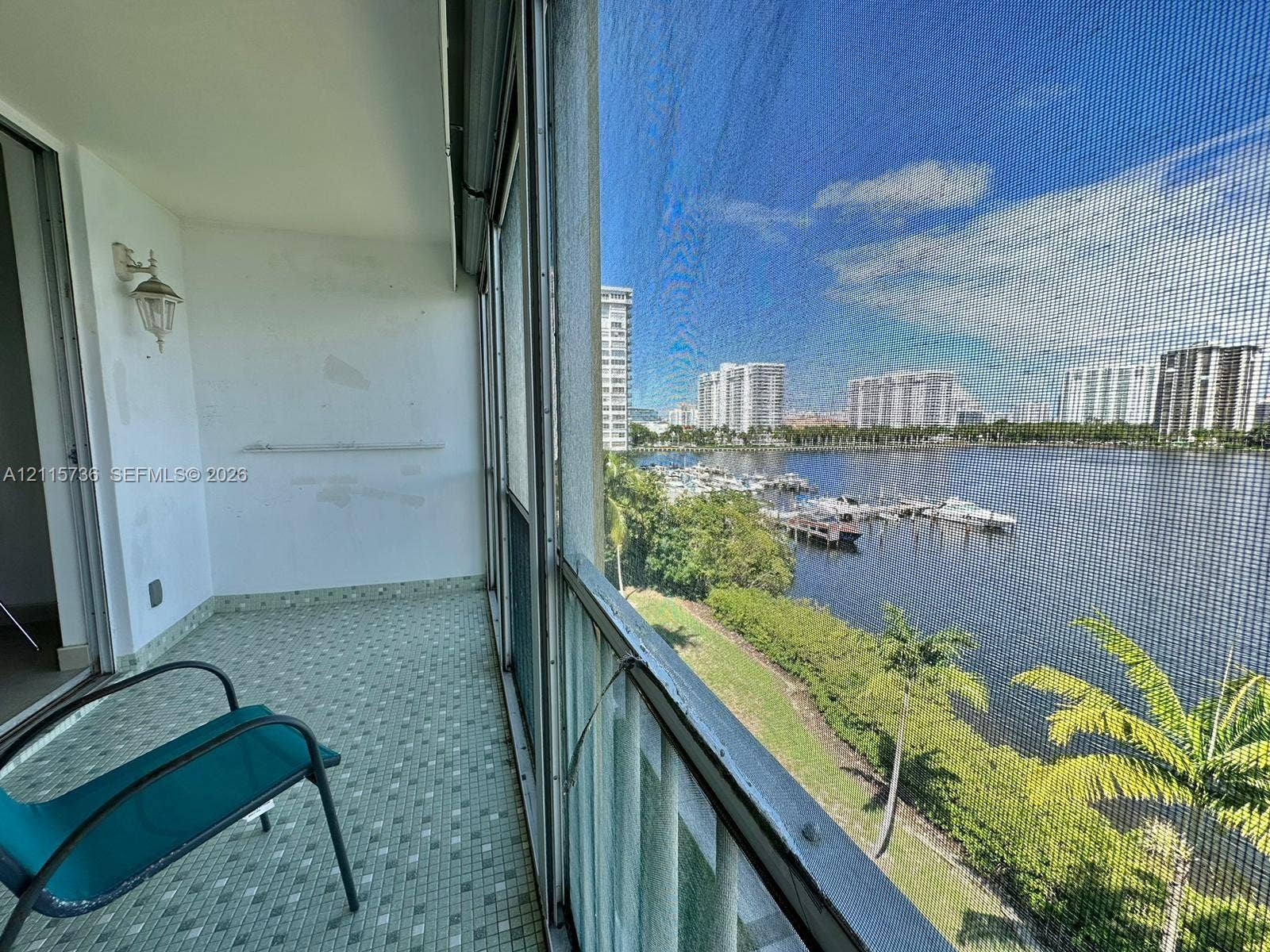 2861 Leonard Drive, #F605, Aventura, FL 33160 Covered balcony featuring screen enclosure, tile flooring, and wall-mounted sconce lighting
