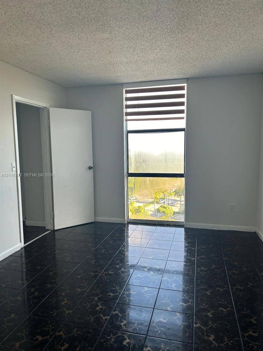 13499 Biscayne Boulevard, #905, North Miami, North Miami, FL 33181 Interior space featuring large-format dark tile flooring, a floor-to-ceiling vertical window, and adjustable horizontal blinds