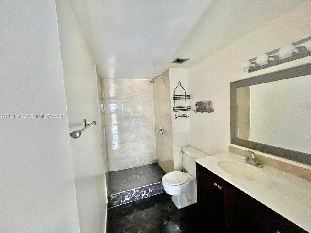13499 Biscayne Boulevard, #905, North Miami, North Miami, FL 33181 Bathroom featuring a vanity with an integrated basin, a framed wall mirror, a walk-in shower with tiled surround, and dark-toned flooring