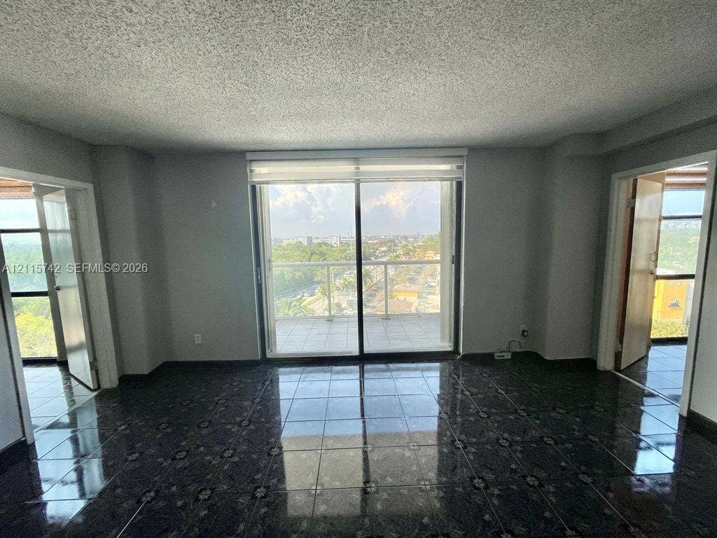 13499 Biscayne Boulevard, #905, North Miami, North Miami, FL 33181 Interior space featuring large-format dark tile flooring, sliding glass doors, and a private balcony with glass railing