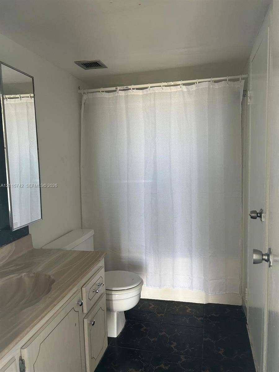 13499 Biscayne Boulevard, #905, North Miami, North Miami, FL 33181 Bathroom featuring a stone-finish countertop, white vanity cabinetry with metal hardware, a wall-mounted mirror, and tile flooring