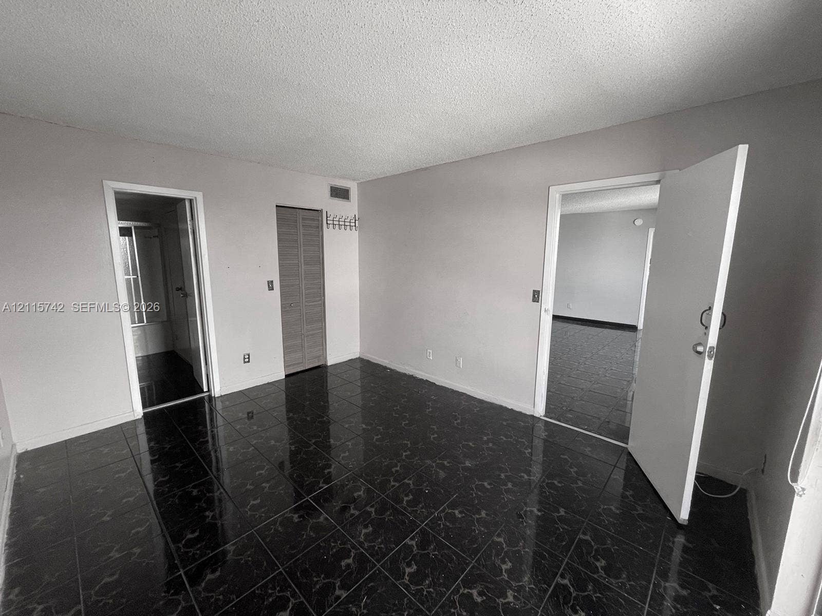 13499 Biscayne Boulevard, #905, North Miami, North Miami, FL 33181 Interior space featuring dark, high-gloss tile flooring, louvered closet doors, and multiple interior doorways