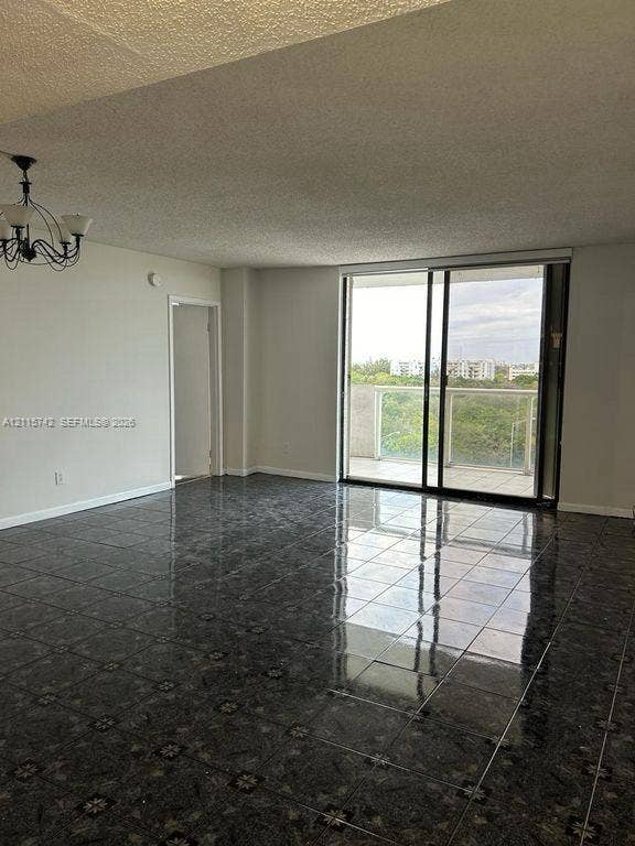 13499 Biscayne Boulevard, #905, North Miami, North Miami, FL 33181 Living area featuring polished tile flooring, black metal chandelier, and floor-to-ceiling sliding glass doors leading to a balcony with glass railings