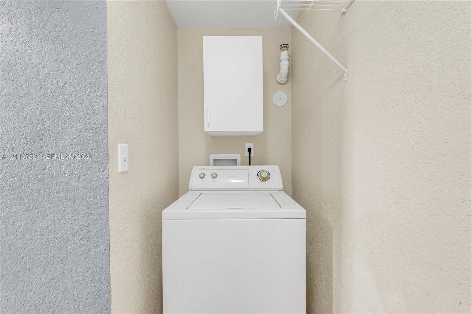 Laundry area featuring a wall-mounted storage cabinet, wire shelving, and dedicated utility hookups