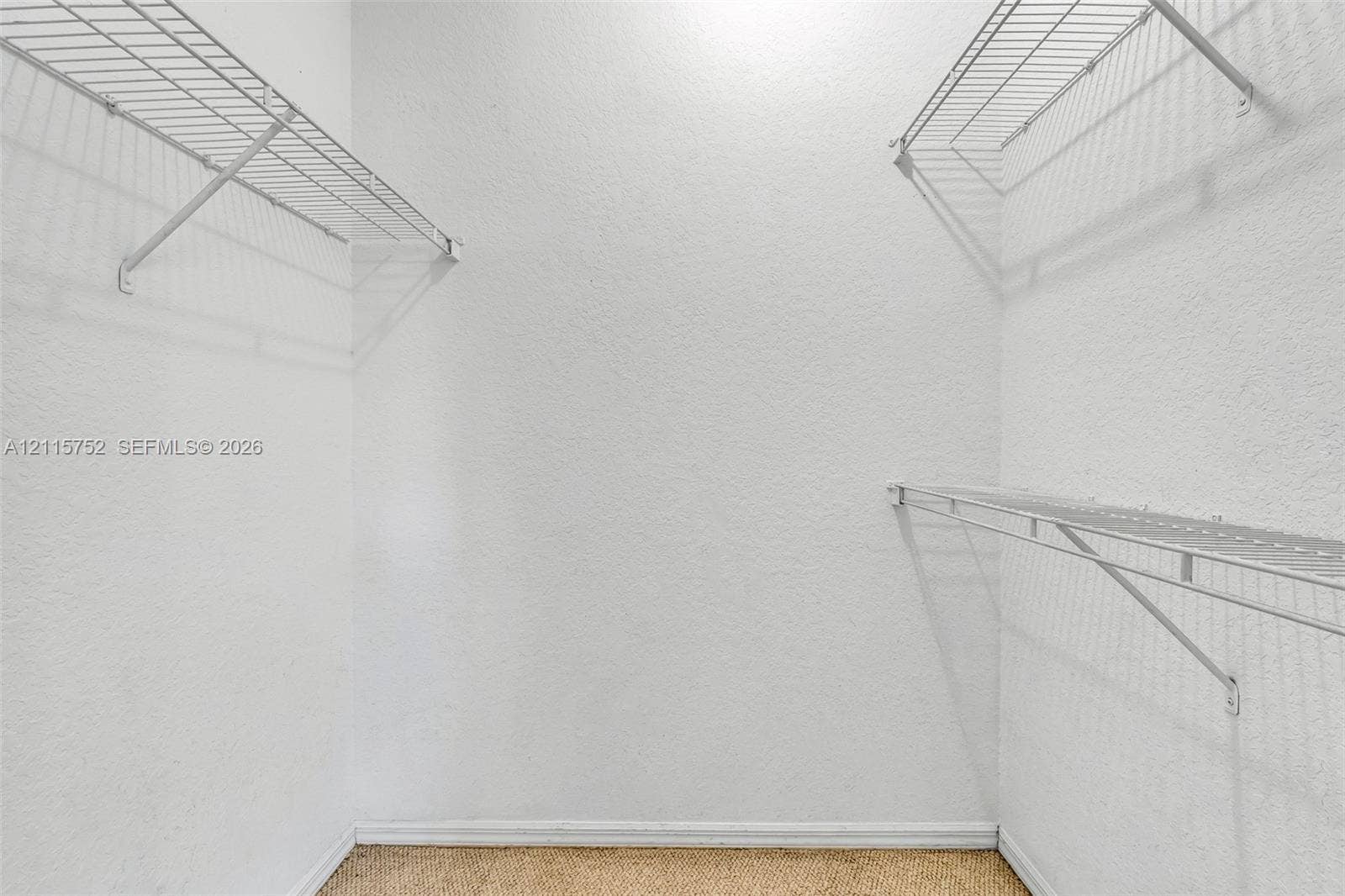 Walk-in closet featuring white walls, textured wall finish, and multi-level white wire shelving