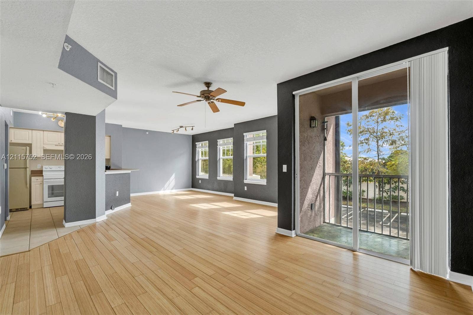 Open floor plan featuring wood-finish flooring, recessed lighting, a ceiling fan, and sliding glass doors with balcony access