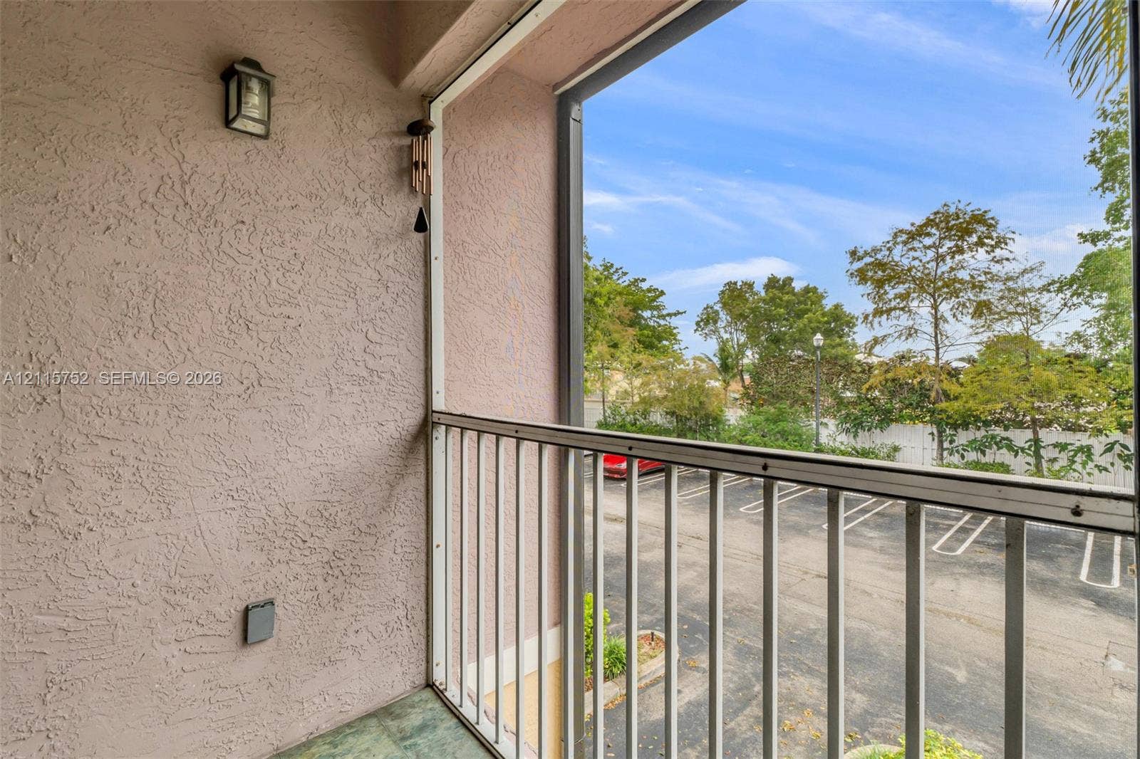 Private balcony featuring stucco walls, a metal railing, tiled flooring, and an attached exterior wall-mounted lantern light