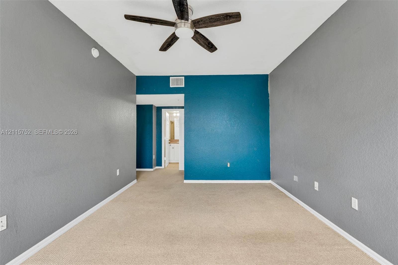 Interior space featuring neutral carpeting, a dual-tone wall finish, and a ceiling fan with integrated lighting