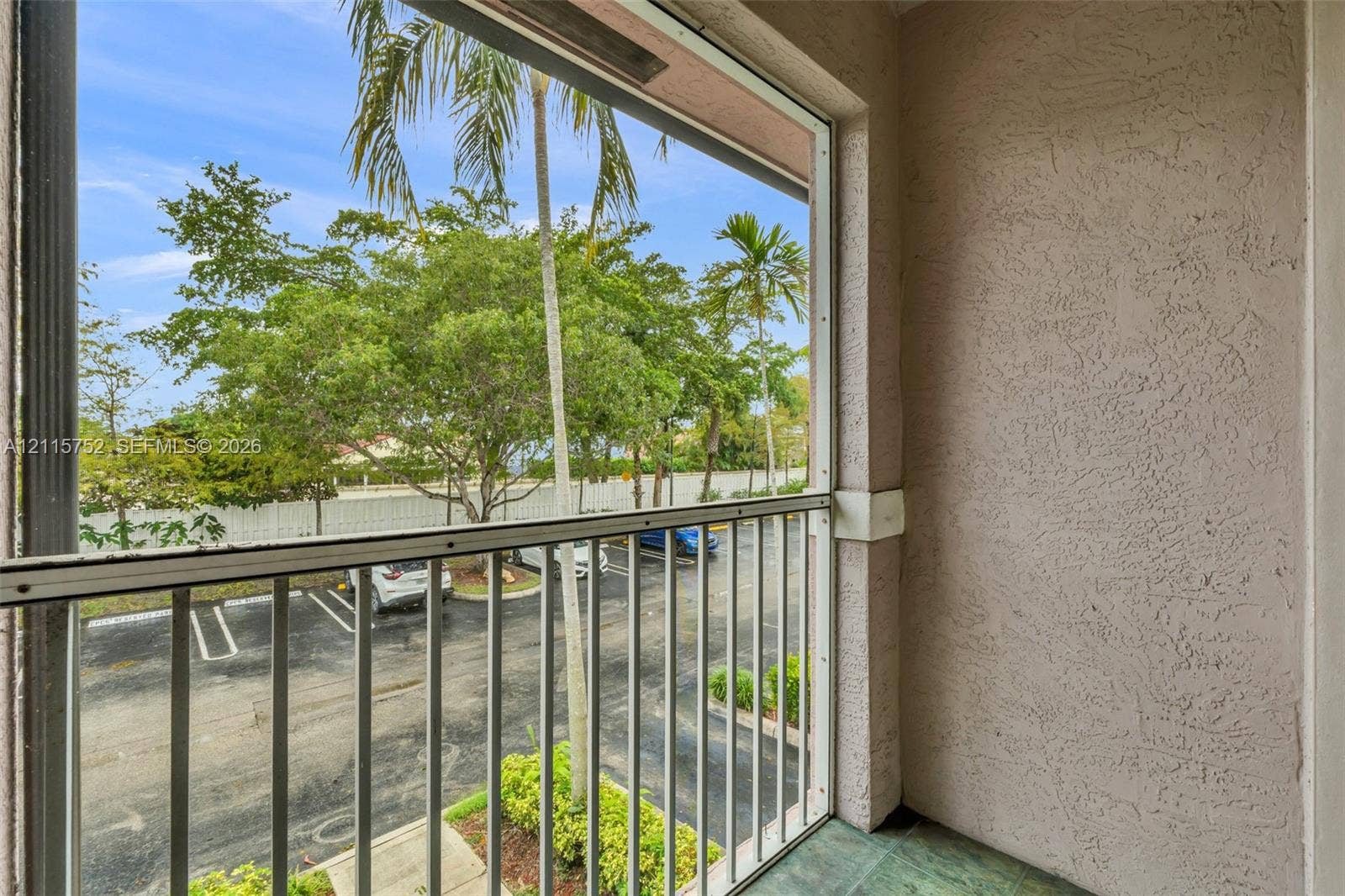 Screened-in balcony featuring stucco walls, vertical metal railing, and stone-finish flooring