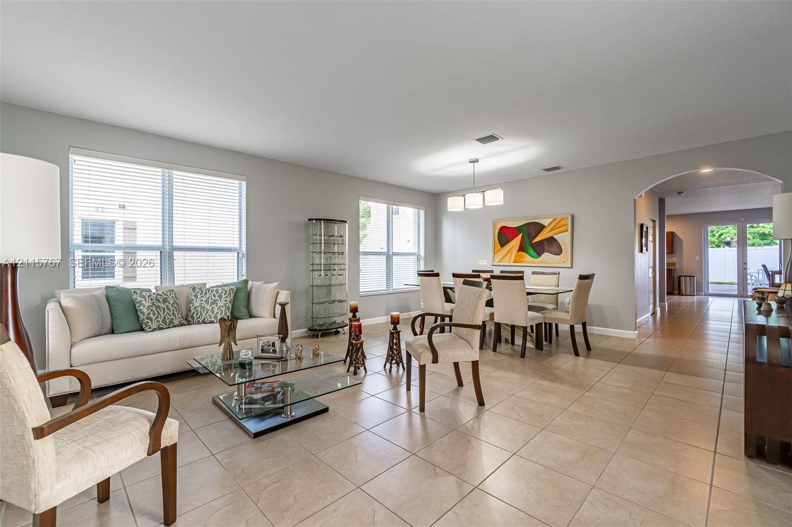 17046 SW 94th Lane, Miami, Miami, FL 33196 Open-concept space featuring large-format ceramic tile flooring, multiple windows providing natural light, a recessed arched entryway, and a built-in three-light modern chandelier