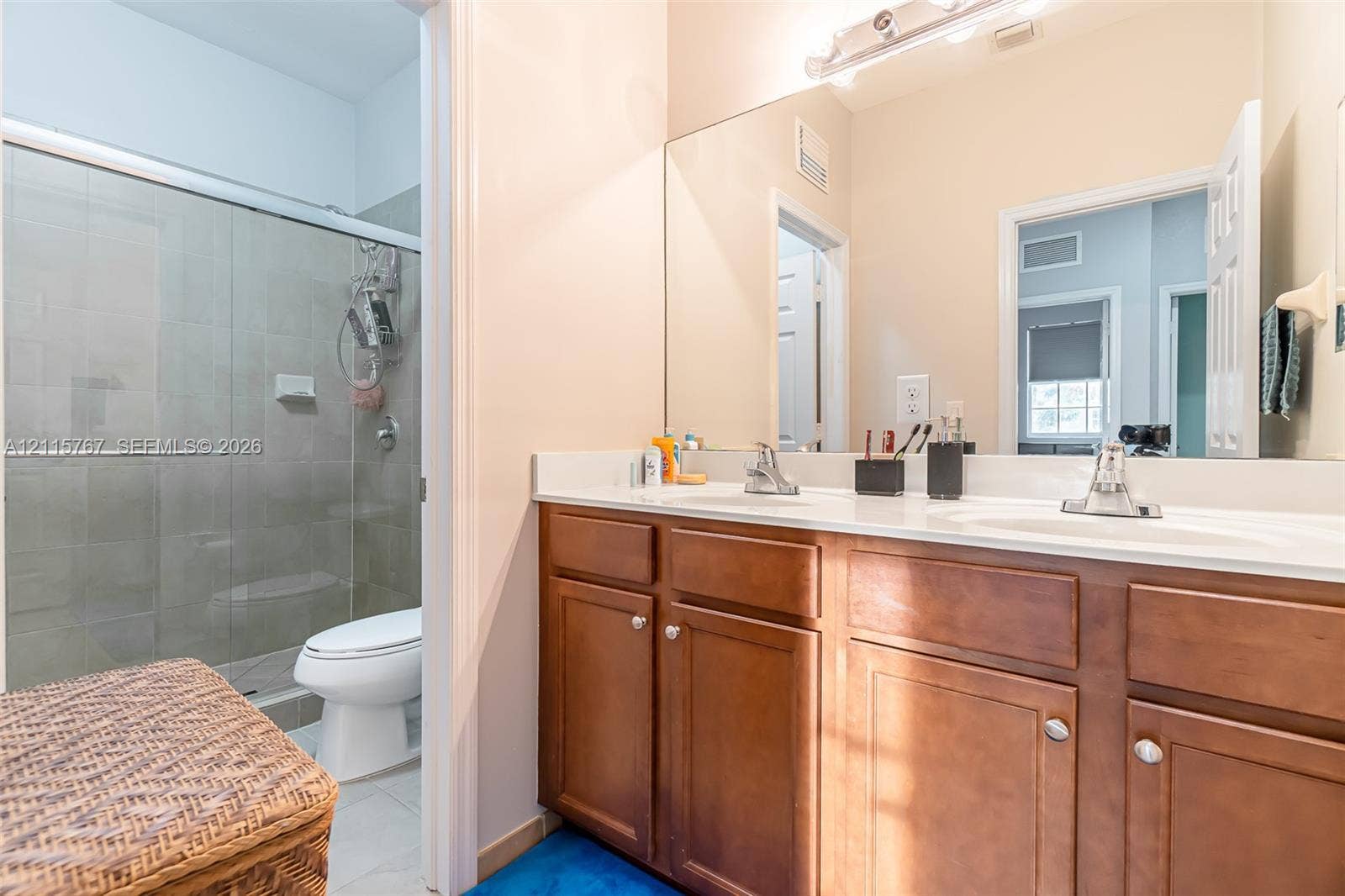 17046 SW 94th Lane, Miami, Miami, FL 33196 Dual-sink vanity with wood-finish cabinetry, solid surface countertops, glass-enclosed shower, and full-width vanity mirror