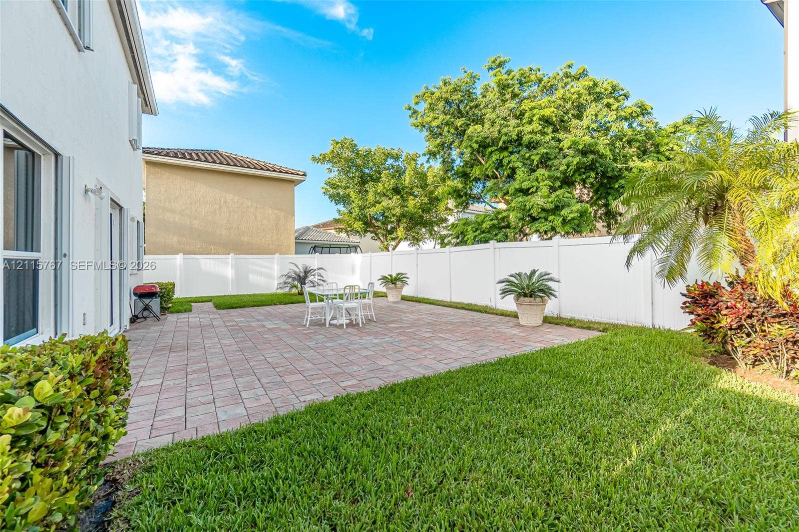 17046 SW 94th Lane, Miami, Miami, FL 33196 Private backyard featuring a paved patio, manicured lawn, perimeter vinyl fencing, and mature landscaping
