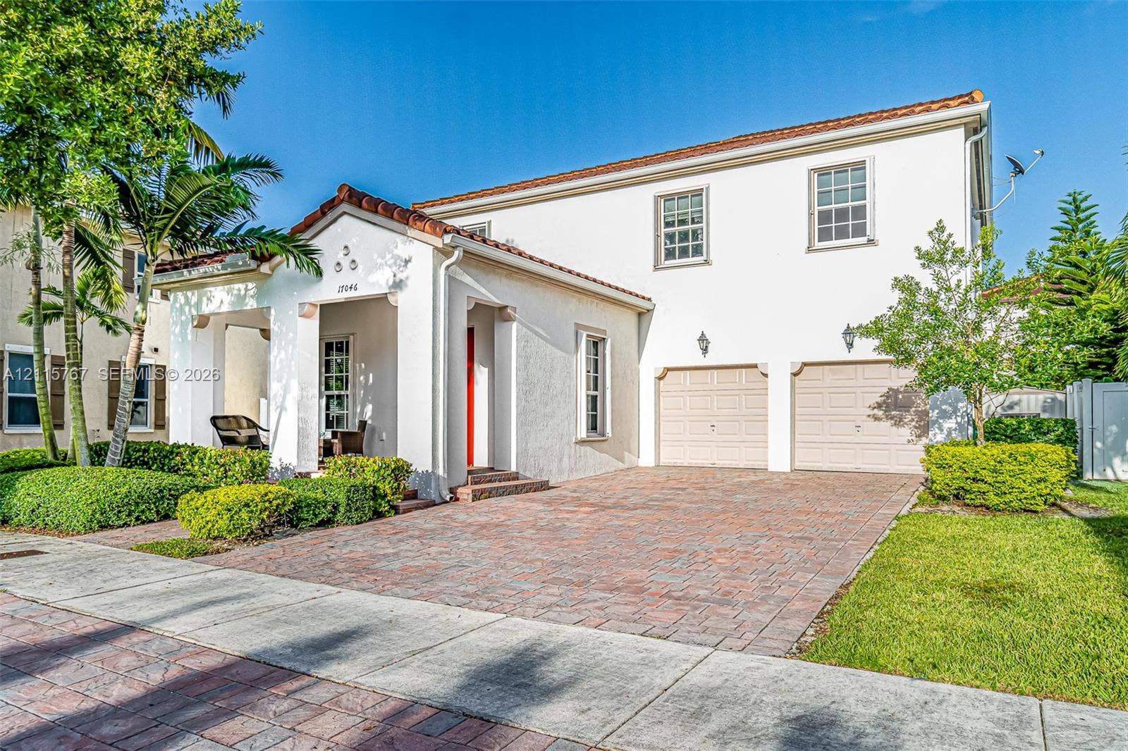 17046 SW 94th Lane, Miami, Miami, FL 33196 Stucco exterior with a tiled roof, covered entryway, and dual-car garage featuring paved driveway and mature landscaping