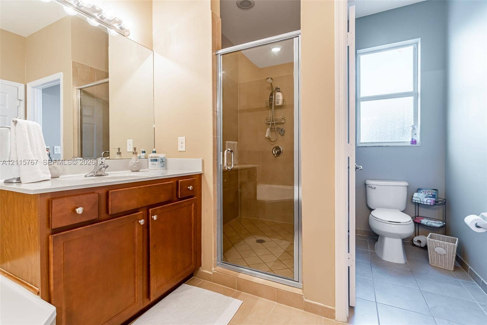 17046 SW 94th Lane, Miami, Miami, FL 33196 Bathroom featuring a wood-finish vanity with a light-toned countertop, a shower with tile surround and glass enclosure, tile flooring, and a window
