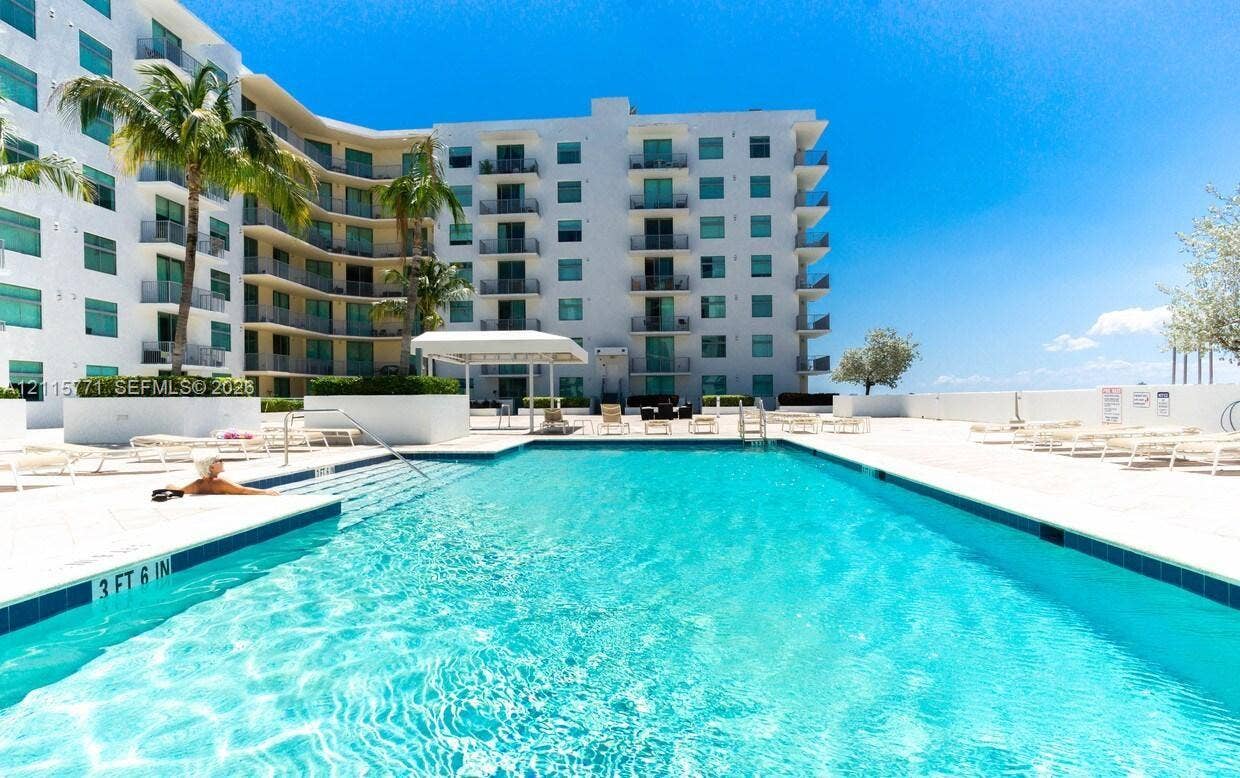 140 S Dixie Highway, #433, Hollywood, Hollywood, FL 33020 Swimming pool with built-in stairs, surrounded by a paved deck, palm trees, and multi-story building exterior