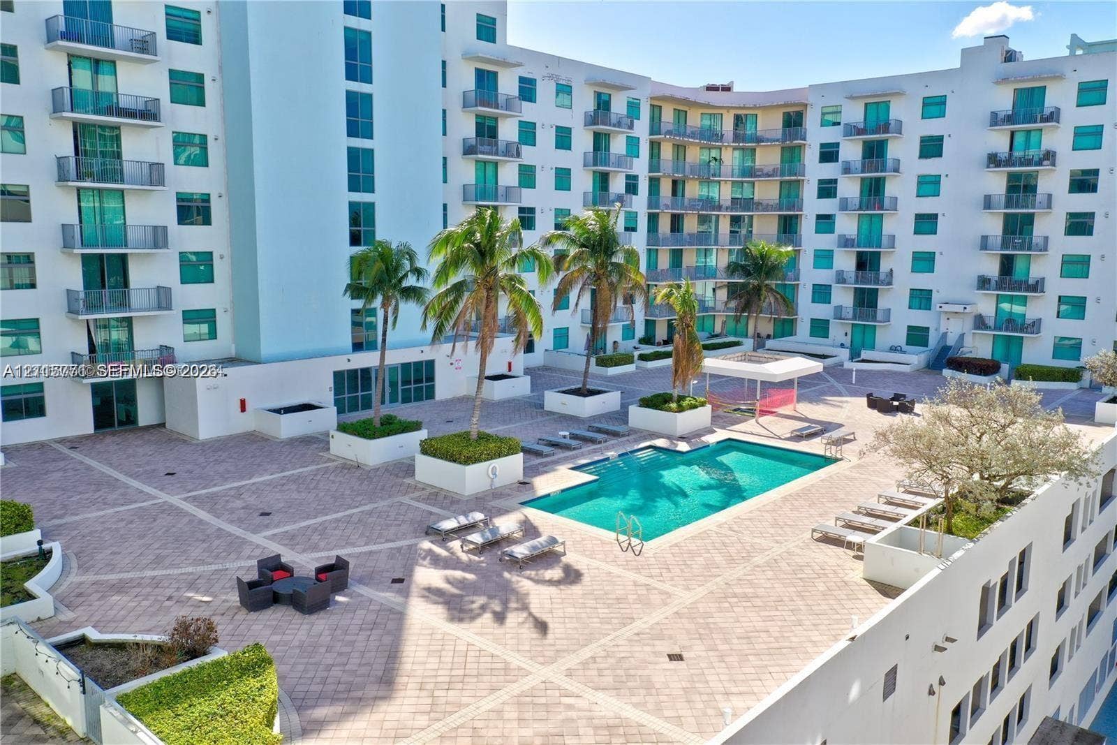 140 S Dixie Highway, #433, Hollywood, Hollywood, FL 33020 Outdoor courtyard featuring a swimming pool, paved sun deck, structured palm tree planters, and a shaded pergola